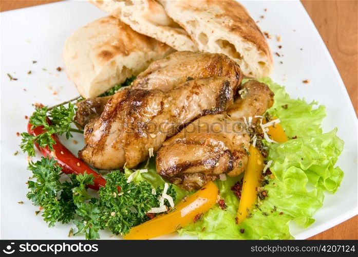 roasted chicken drumstick garnished with fresh green salad, pepper and greens