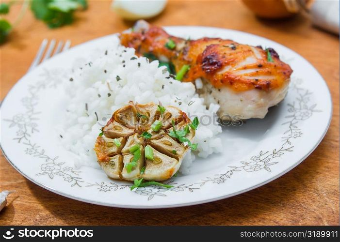 roasted chicken drumstick garnished with rice on wooden table