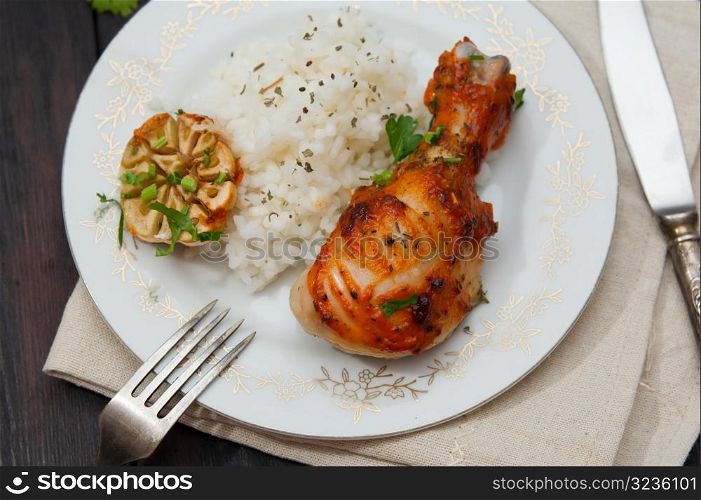 roasted chicken drumstick garnished with rice on wooden table
