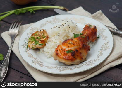 roasted chicken drumstick garnished with rice on wooden table