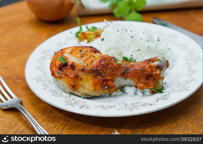 roasted chicken drumstick garnished with rice on wooden table