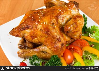 roasted chicken garnished with fresh tomatoes, green salad, pepper and greens