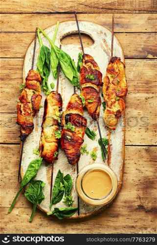 Roasted chicken meat on kitchen board. Chicken breast on a skewer. Meat kebab or shashlik with peanut sauce.. Chicken breast skewers, chicken satay