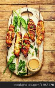 Roasted chicken meat on kitchen board. Chicken breast on a skewer. Meat kebab or shashlik with peanut sauce.. Chicken breast skewers, chicken satay
