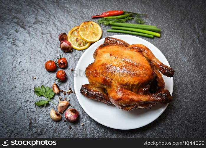 Roasted chicken on plate / baked whole chicken grilled with on herbs and spices and dark background