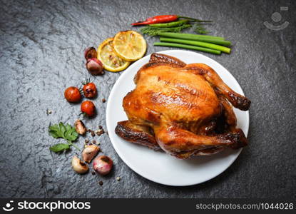 Roasted chicken on plate / baked whole chicken grilled with on herbs and spices and dark background