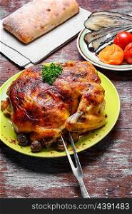 Roasted chicken on wooden plate. Whole roasted chicken with baked vegetables on wooden background