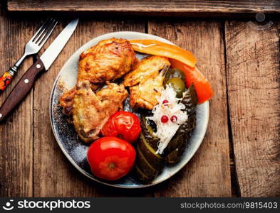 Roasted chicken pieces with marinated vegetables. Rustic style. Baked chicken meat and pickles.
