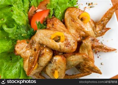roasted chicken wings garnished with fresh green salad, pepper and greens