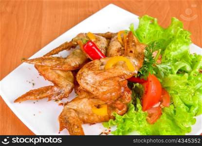 roasted chicken wings garnished with fresh green salad, pepper and greens