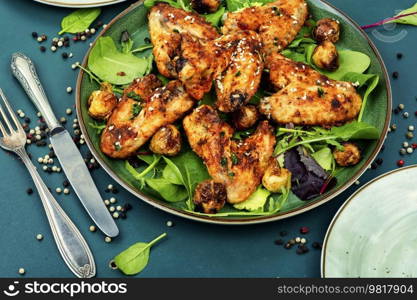 Roasted chicken wings with vegetables on a plate. Baked chicken wings, barbecue