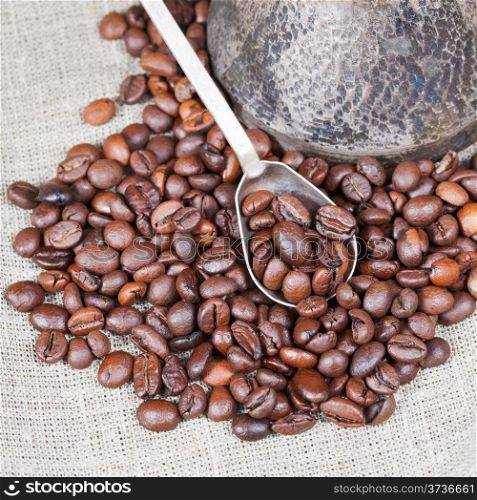 roasted coffee beans and copper coffee pot close up on textile