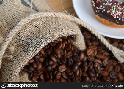 Roasted coffee beans in jute sack on hessian background