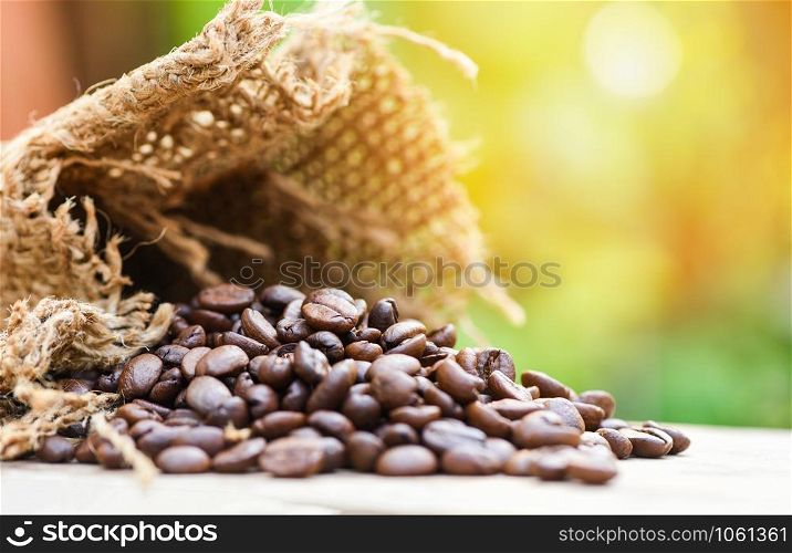 Roasted coffee beans in sack / Closeup macro of coffee beans on wooden and nature sunlight background