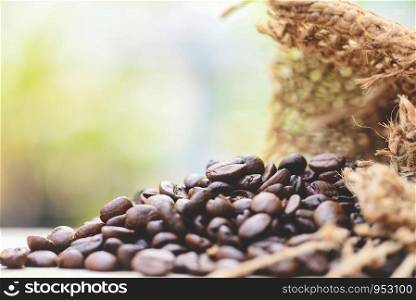Roasted coffee beans in sack / Closeup macro of coffee beans on wooden and nature sunlight background