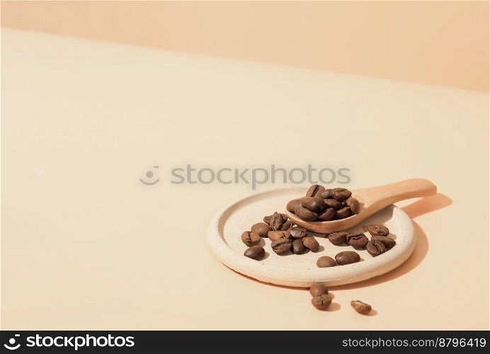 roasted coffee beans on a trendy concrete plate with wooden spoon on beige backgound. roasted coffee beans on a trendy concrete plate with wooden spoon on beige backgound. 