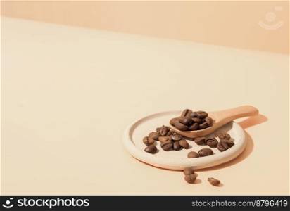 roasted coffee beans on a trendy concrete plate with wooden spoon on beige backgound. roasted coffee beans on a trendy concrete plate with wooden spoon on beige backgound. 