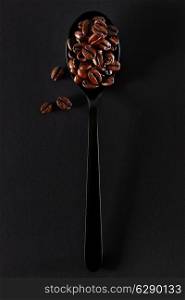 Roasted coffee beans on black spoon