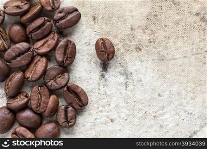 Roasted coffee beans on dirty canvas with copy - space