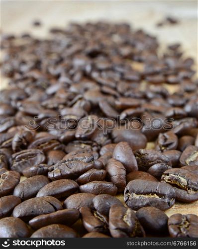Roasted coffee beans scattered on a wooden board