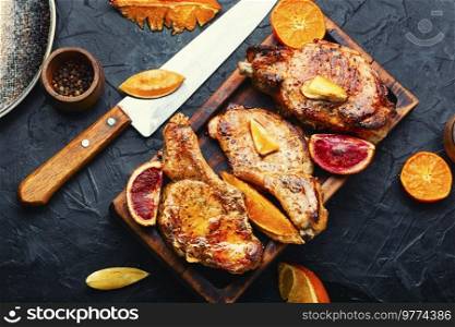 Roasted delicious meat in orange sauce. Pork on the bone. Meat grilled with citrus fruits