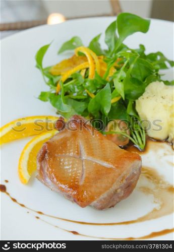 Roasted duck breast served with mashed potatoes and orange , fresh salad and white wine sauce