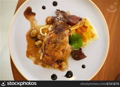 Roasted duck leg in prune sauce with potatoes . Roasted duck leg in prune sauce