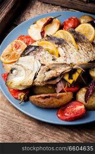 Roasted fish and vegetables on vintage wooden table. Grilled fish with lemon and potato