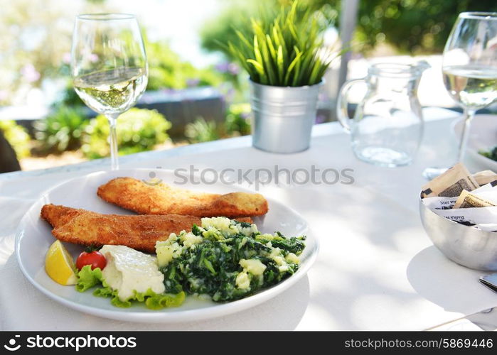 roasted fish, vegetables on dish and glass with wine