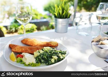 roasted fish, vegetables on dish and glass with wine