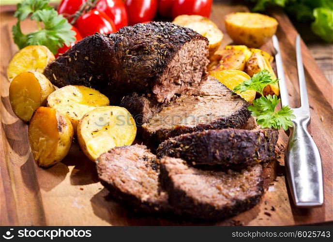 roasted meat with vegetables on wooden board