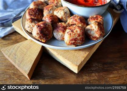Roasted meatballs with tomato sauce , delicious meat cutlets on wooden table . Top view .. Roasted meatballs with tomato sauce , delicious meat cutlets on wooden table. Top view