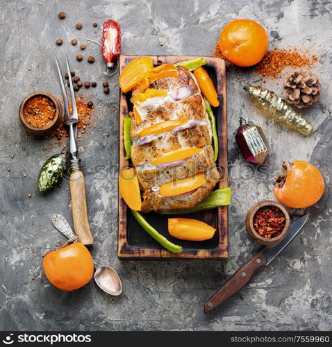 Roasted of pork with persimmon on a cutting board.Holiday food. Christmas baked pork,xmas