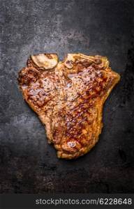 Roasted or grilled T-bone steak on on dark rust metal background, top view, close up