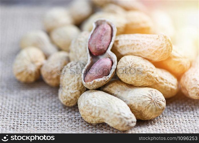 Roasted peanuts on a wooden bowl and sack background / Peanut in shells for food or snack