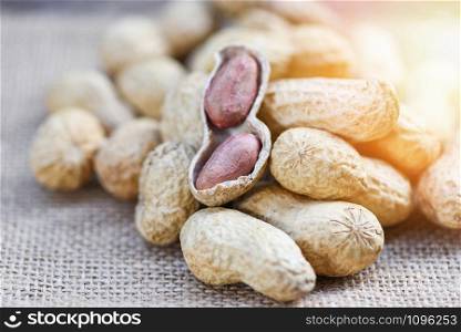 Roasted peanuts on a wooden bowl and sack background / Peanut in shells for food or snack