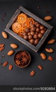Roasted pecans and macadamia nuts, dried tangerine, dried berries on a dark concrete background