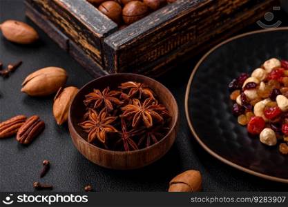 Roasted pecans and macadamia nuts, dried tangerine, dried berries on a dark concrete background