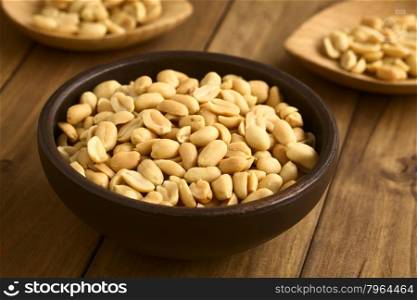 Roasted peeled peanuts in rustic bowl, photographed with natural light (Selective Focus, Focus one third into the peanuts in the bowl)