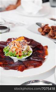 Roasted Peking duck or Beijing duck crispy skin with sweet Hoisin sauce and salad on white plate. close up shot