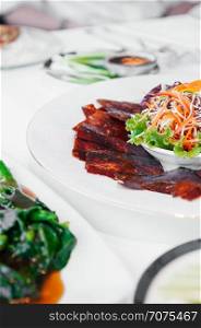 Roasted Peking duck or Beijing duck crispy skin with sweet Hoisin sauce and salad on white plate. close up shot