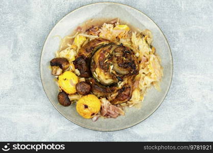 Roasted pork knuckle eisbein with cabbage and apples. Pork leg, German food, top view. Pork knuckle prepared in sauerkraut.