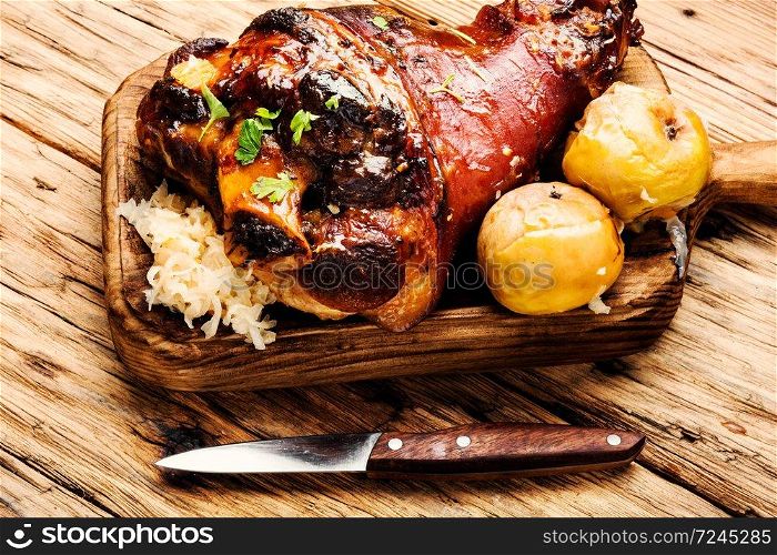 Roasted pork knuckle on wooden cutting board.Oktoberfest menu.. Roasted pork knuckle