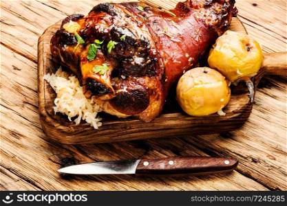 Roasted pork knuckle on wooden cutting board.Oktoberfest menu.. Roasted pork knuckle