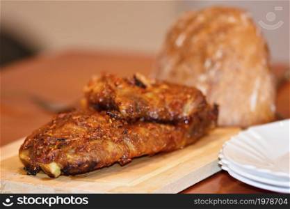 Roasted pork ribs. On wooden background bread.