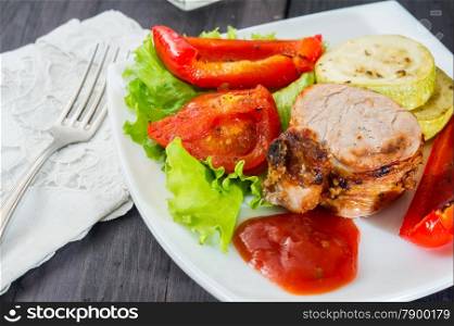 roasted pork steak with grilled vegetables on white plate