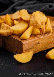 Roasted potato wedges on wooden board