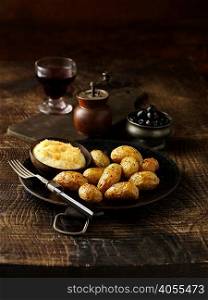 Roasted potatoes with bowl of parmesan fondue on rustic dish
