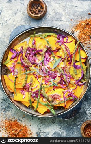 Roasted pumpkin sliced in pieces with vegetables in pan.Traditional autumn dishes from pumpkin. Baked pumpkin with vegetables