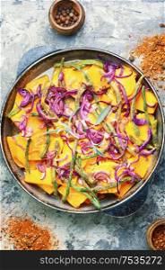 Roasted pumpkin sliced in pieces with vegetables in pan.Traditional autumn dishes from pumpkin. Baked pumpkin with vegetables